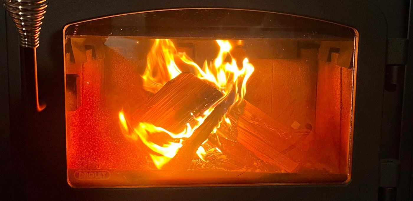 Flames curling around split logs behind the glass door of the sauna's wood stove